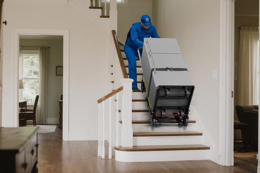 Delivery worker using Riosoc electric stair climbing hand truck to move a refrigerator upstairs