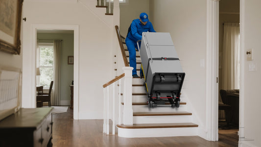 Technician using Riosoc electric stair climber to move a refrigerator down residential stairs