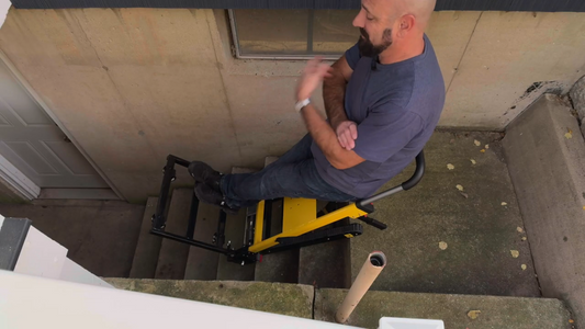 A person using the Riosoc electric stair climber hand truck to effortlessly ascend outdoor steps, demonstrating the smooth operation and reduced physical strain of the track-based system.